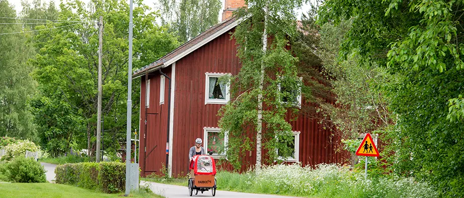 En person som cyklar framför ett rött hus