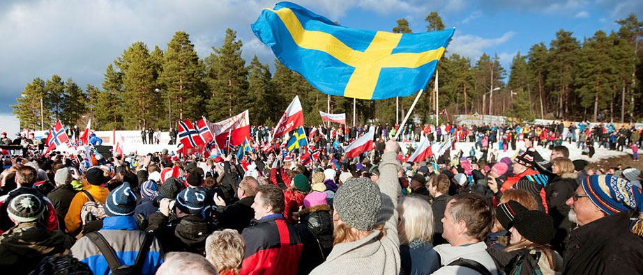 Man vinkar med svensk flagga på skidstadion på Lugnet.