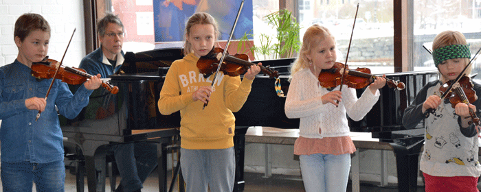 Fem barn står på en rad och spelar fiol