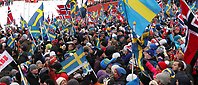 Storpublik med svenska och norska flaggor vajande i vinden på skidstadion under skid-VM 2015.
